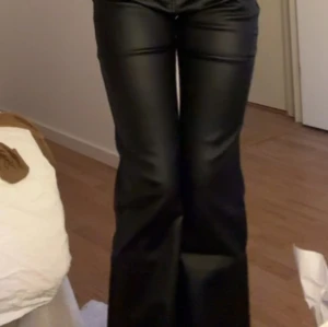 Svarta skinnbyxor - Snygga svarta skinnbyxor med en tight passform upptill och utsvängda ben. Perfekta för en trendig look med en glansig finish. Använd 1 gång