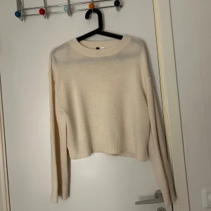 Beige stickad tröja från H&M - Säljer en mysig beige stickad tröja från H&M. Tröjan har en croppad passform och långa ärmar, perfekt för kyligare dagar. Enkel och stilren design som passar till det mesta.
