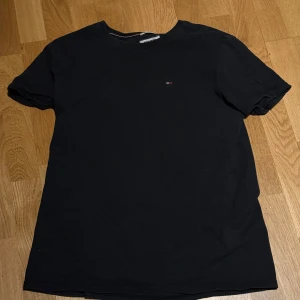Svart t-shirt från Tommy Jeans - Snygg svart t-shirt från Tommy Jeans med liten logga på bröstet. Perfekt för en casual look. Tillverkad i mjukt material för extra komfort. Kan diskutera pris