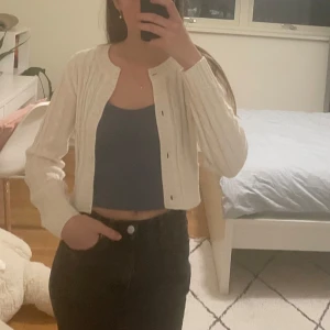 Vit stickad kofta från H&M - Säljer en söt vit stickad kofta från H&M. Koftan är croppad med knappar framtill och har ett ribbat mönster🤍