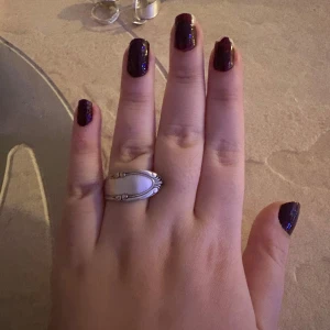 Unik ring  i silver - Säljer ett unikt ring i silver med en elegant, böjd design som påminner om en gammaldags sked. Perfekt för att ge en vintagekänsla till din stil. Armbandet har en slät yta med dekorativa detaljer på kanterna. Gjort av sked