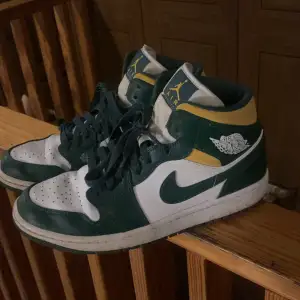 Snygga Nike Air Jordans i grönt och gult med vita detaljer. Skorna har klassisk snörning och en hög design som ger bra stöd. Perfekta för dig som vill ha en stilren och sportig look.
