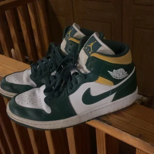 Nike Air Jordans i grönt och gult - Snygga Nike Air Jordans i grönt och gult med vita detaljer. Skorna har klassisk snörning och en hög design som ger bra stöd. Perfekta för dig som vill ha en stilren och sportig look.