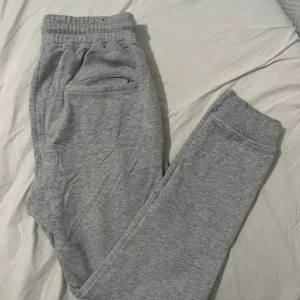 Grå mjukisbyxor från FSBN - Säljer ett par grå mjukisbyxor från FSBN i storlek XS. Byxorna har en elastisk midja och muddar vid bensluten för extra komfort. Perfekta för en avslappnad stil.