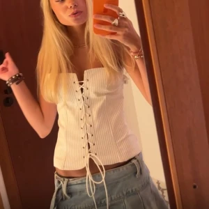 korsettopp - Snygg vit ribbad korsettopp med snörning framtill. Perfekt för en trendig look. Passar bra till både kjol och jeans.