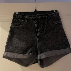 Svarta högmidjade jeansshorts - Snygga svarta högmidjade jeansshorts från New yorker i storlek XS. De har en cool tvättad look och knappar framtill. 
