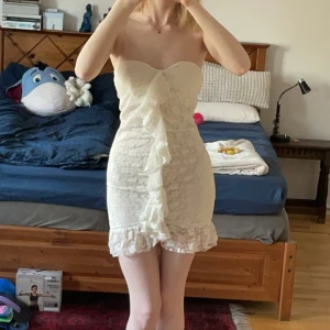 Vit spetsklänning från Gina Tricot - Säljer en söt vit spetsklänning från Gina Tricot i storlek XS. Klänningen är axelbandslös med en volangdetalj framtill och har en kort längd. Perfekt för studenten. Säljer då den är lite stor för mig. Bara att höra av dig om du har några frågor🩵