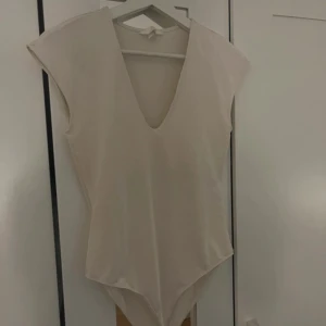vit bodysuit - En vit bodysuit med v-ringning och korta ärmar i storlek S.💞