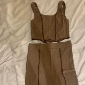 Matchande sett kjol och topp - Ett sett med brun kjol och topp. Kjolen är kort och slut precis under bilden men det fick inte plats på bilden. Settet är använt 2 gånger. Storlek s men passar även mig som har xs 