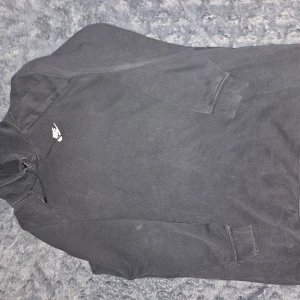 Svart hoodie från Nike - Säljer en stilren svart hoodie från Nike med klassisk logga på bröstet. Tröjan har en bekväm passform med långa ärmar och en praktisk känguruficka framtill. Perfekt för en avslappnad look.