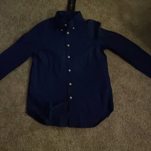 Mörkblå skjorta från Ralph Lauren - Snygg mörkblå skjorta från Ralph Lauren med klassisk krage och knappar framtill. Perfekt för en stilren look.