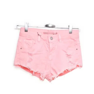 Rosa jeansshorts med slitningar - Snygga rosa jeansshorts med slitna detaljer och fransig kant. Perfekta för en avslappnad sommarlook. De har en knapp och dragkedja framtill samt klassiska fem fickor. Pris är diskuterbart!🥰 skulle säga att dom är i storlek xs/s.
