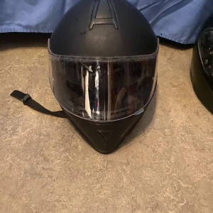 Svart hjälm från NASU - Säljer en svart hjälm från NASU med visir. Hjälmen har en stilren design och justerbart hakband för säker passform. Perfekt för motorcykelentusiaster.