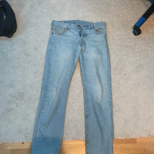 Levi's 501 ljusblå jeans - Säljer ett par klassiska Levi's 501 jeans i ljusblå denim. De har en rak passform och är midwaist. Perfekta för en avslappnad stil. Jeansens ikoniska design gör dem tidlösa och lätta att matcha med olika outfits.