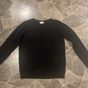 Svart tröja - Säljer en klassisk svart tröja med långa ärmar. Perfekt för kyligare dagar och enkel att matcha med olika outfits. Tröjan har ribbade muddar vid ärmslut och nederkant.