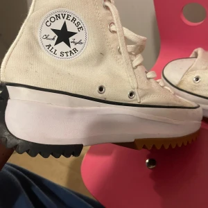 Vita Converse All Star sneakers - Snygga vita Converse All Star sneakers med hög sula och klassisk snörning. Skorna har en unik sicksackmönstrad sula i gummi som ger extra grepp. Perfekta för en avslappnad stil.