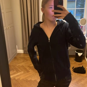 Mörkblå hoodie från Soft Goat - Säljer en stilren mörkblå hoodie från Soft Goat i 100% kashmir. Tröjan har en dragkedja framtill och långa ärmar, perfekt för kyliga dagar. Den är både mjuk och bekväm, idealisk för en avslappnad look.