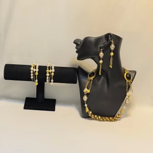 Elegant smyckeset med pärlor och svarta stenar - Snyggt smyckeset med halsband, örhängen och armband. Setet har guldiga kedjor, vita pärlor och svarta ovala stenar. Perfekt för att ge en elegant touch till din outfit.Ett par örhängen och ett par armband plus en halsband handgjorda mycket mycket fint nytt oanvänd 