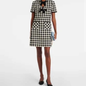 Svartvit rutig klänning med rosett - Elegant svartvit rutig klänning från MaxMara med korta ärmar och en söt rosett vid halsen. Klänningen har en klassisk A-linjeform och praktiska fickor framtill. Perfekt för en stilren look.