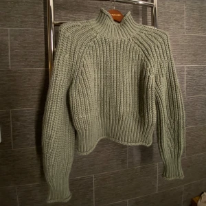 Grön stickad tröja från H&M - Grön stickad tröja från H&M. Tröjan har en hög krage och långa ärmar. Det stickade materialet ger absolut inte en störande känsla utan är väldigt mjuk. 