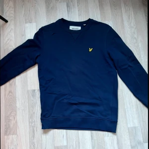 Mörkblå tröja från Lyle & Scott - Säljer en stilren mörkblå tröja från Lyle & Scott. Perfekt för en avslappnad look.