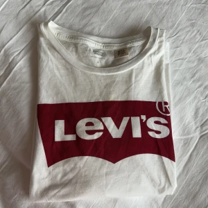 Vit t-shirt från Levi's -  t-shirt från Levi's med det klassisk logo. Mindre missfärgning och fläck nära krage och logo. Se bild. Passar small/medium