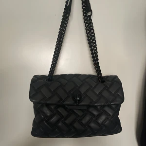 Svart quiltad axelväska från Kurt Geiger - Snygg svart axelväska från Kurt Geiger, lite slitage på kedjan annars är den i bra skick. Väskan är i den större storleken (nypris 3500kr)