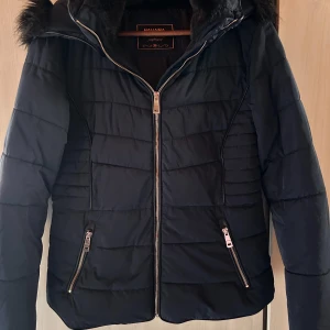 Snygg mörkblå täckjacka från Havana!  - Snygg figursydd mörkblå täckjacka med fickor fram och huva med fuskpäls från Havana i storlek 36/S. Nyskick!