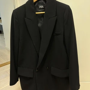 Svart kavaj från Zara - Oversized svart kavaj från Zara med klassisk design. Kavajen har breda slag och dubbla knappar framtill. 