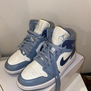 Nike Air Jordans i blått och vitt - Säljer ett par stilrena Nike Air Jordans i blått och vitt. Skorna har en klassisk design med snörning och den ikoniska Air Jordan-loggan på sidan. Perfekta för dig som vill ha en sportig och trendig look.