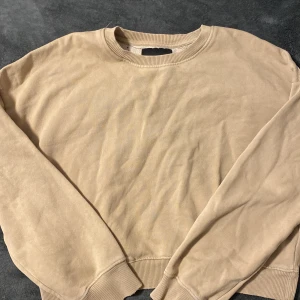Beige sweatshirt - Säljer en stilren beige sweatshirt med rund halsringning. Tröjan har långa ärmar och ribbade muddar vid ärmslut och nederkant. Perfekt för en avslappnad look.