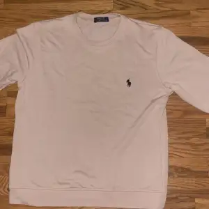 Säljer en stilren vit tröja från Polo Ralph Lauren med det klassiska logotypbroderiet på bröstet. Tröjan har långa ärmar och en rund halsringning. Perfekt för en avslappnad och snygg look.