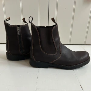 Bruna boots från Kavat - Snygga bruna boots från Kavat i skinn med dragkedja på sidan för enkel på- och avtagning. Perfekta för höst och vinter med en robust sula för bra grepp. Stilren design med diskreta sömmar och praktiska dragflikar. Använd väldigt få gånger. 