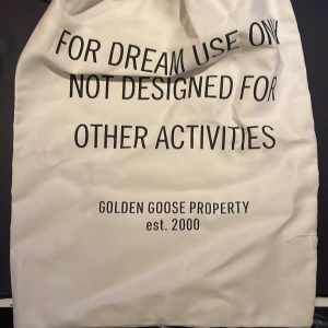 Vit påse från Golden Goose - Vit påse med texten 'FOR DREAM USE ONLY NOT DESIGNED FOR OTHER ACTIVITIES' från Golden Goose Property, est. 2000. Perfekt för att förvara eller transportera dina skor med stil.