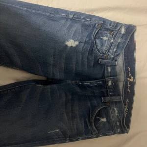 Blå lågmidiade jeans med slitningar - Snygga lågmidiade jeans med lite slitningar. Pris kan diskuteras💕