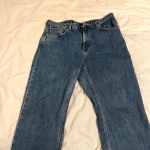 Blå jeansbyxor - Säljer ett par klassiska blå jeansbyxor från weekday med fem fickor och knappgylf. Perfekta för en avslappnad stil.