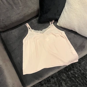 Ljusrosa linne med spetsdetaljer - Säljer ett ljusrosa linne med smala axelband och vacker spetsdetalj vid halsringningen💕