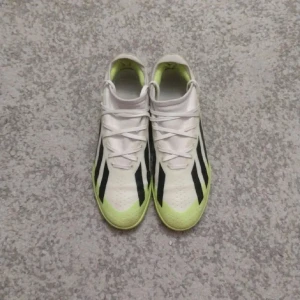 Adidas fotbollsskor i vitt och neongrönt - Snygga Adidas fotbollsskor i vitt med neongröna och svarta detaljer. Skorna har snörning och en modern design som passar perfekt för inomhus. Nypris 1200. Denna storleken är väldigt stor efterfrågan och detta är slut i överallt.  Vi kan diskutera om priset. 