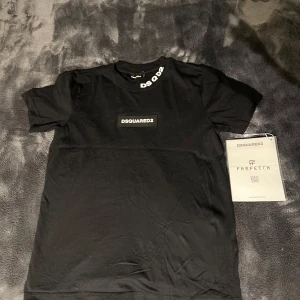 Svart t-shirt från Dsquared2 - Snygg svart t-shirt från Dsquared2 med tryckt logga på bröstet och text på kragen. Perfekt för en stilren look. Passar bra till jeans eller shorts.