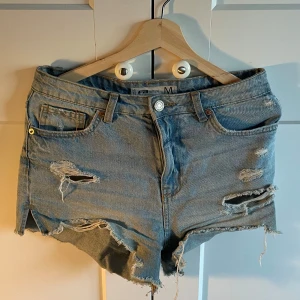 Blå jeansshorts - Säljer ett par blå jeansshorts från new yorker. De har en snygg slitning och fransiga kanter.