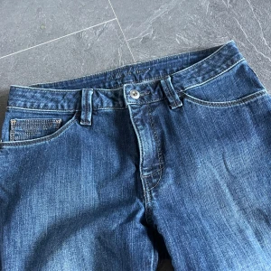Blå jeans med strassdetaljer - Snygga blå jeans med strassdetaljer på bakfickorna. Jeansen är raka men inte så utsvängda . Midrise. 