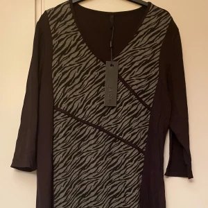 *NY*Svart klänning med zebramönster i stl 46 från Jensen DK, presenttips  - Ny finklänning, normal i stl, jag har stl 44 o den blev för stor för mig.  Mkt bra kvalitet, mjuk och skön viskos. Formar sig fint efter kroppen. Perfekt för en stilren look med en touch av djurmönster. Nypris: 700 sek, Pris nu: 120 sek. 