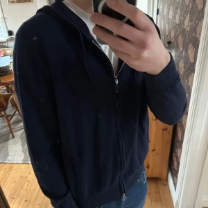 Mörkblå hoodie med dragkedja - Säljer en stilren mörkblå hoodie med dragkedja. Tröjan har långa ärmar och en praktisk huva. Perfekt för en avslappnad look.skick 8/10 inga defekter. Skriv vid frågor 🙌