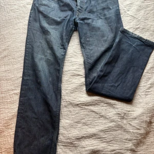 Blå jeans från Diesel - Snygga blå jeans från Diesel med klassisk femficksdesign och knappgylf. Perfekta för en avslappnad stil. Märkesdetalj vid fickan ger en extra touch.