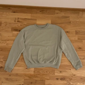 Grön sweatshirt - Säljer en stilren grön sweatshirt med rund hals och långa ärmar. Perfekt för en avslappnad look. Passar bra till jeans eller joggers.