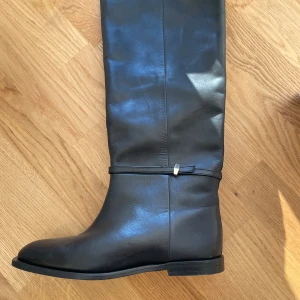 Svarta stövlar från H&M Premium Selection - Snygga svarta stövlar i skinn från H&M Premium. De har en stilren design med en diskret remdetalj runt ankeln. Perfekta för både höst och vinter.