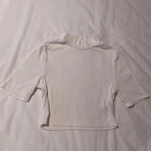 Vit ribbad polotopp - Säljer en stilren vit ribbad polotopp med korta ärmar. Perfekt för lager-på-lager eller att bära som den är. Enkel design som passar till det mesta. Sitter väldigt bra och extremt stretchigt material. Kontakta mig om du har frågor☺️