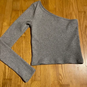 Grå oneshoulder topp - Snygg grå/silver oneshoulder topp med ribbad textur och lång ärm. 