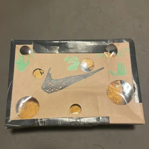 Dunks  - Säljer ett par vita Nike sneakers med unik design och textdetaljer på sidan. Skorna har snörning och en extra snörningsdetalj över ovansidan. Perfekta för dig som gillar en stilren men ändå iögonfallande look. Dunks, knappt använda, passade inte direkt.