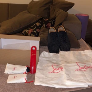 Midnight navy sneakers från Christian Louboutin - Snygga mörka blåa sneakers från Christian Louboutin med ikoniska röda sulor. Skorna har en cool design med svarta nitar på ovandelen och snörning. Perfekta för att ge en edgy touch till din stil. Och till grisch stilen som är trendig med storlek sitter tight 41/42.5 nytt skick 